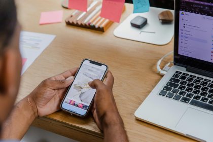A person multitasking with a smartphone and laptop at an office desk, showcasing productivity.