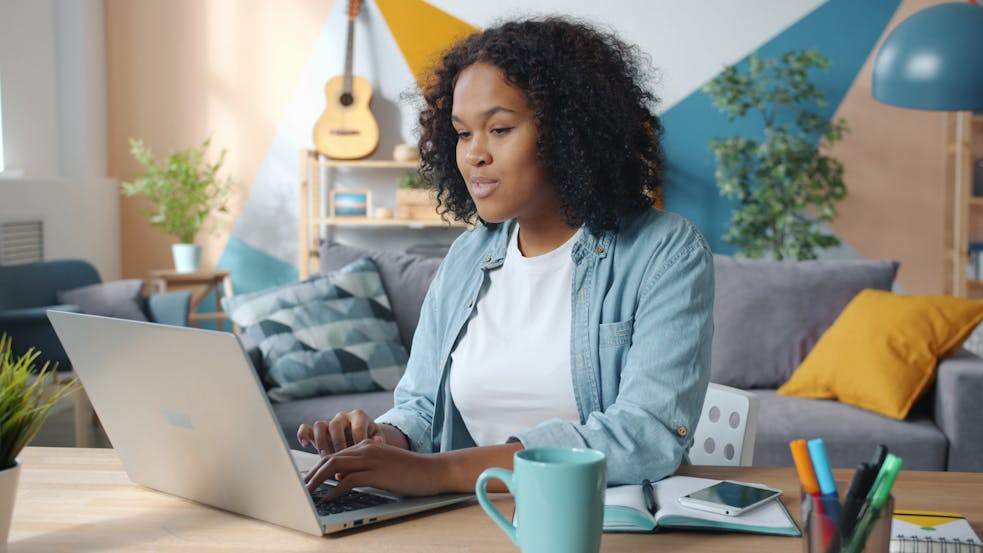 Focused woman using laptop in a modern, colorful home office setting.